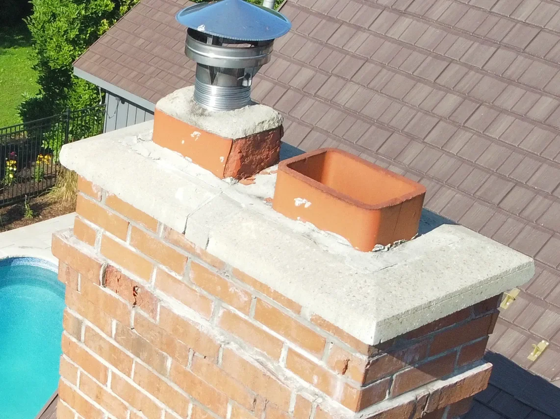 Chimney cap and flue area with visible roofline context.
