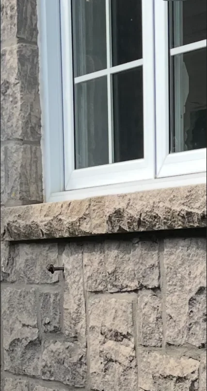 Window sill installation detail with surrounding stone masonry.