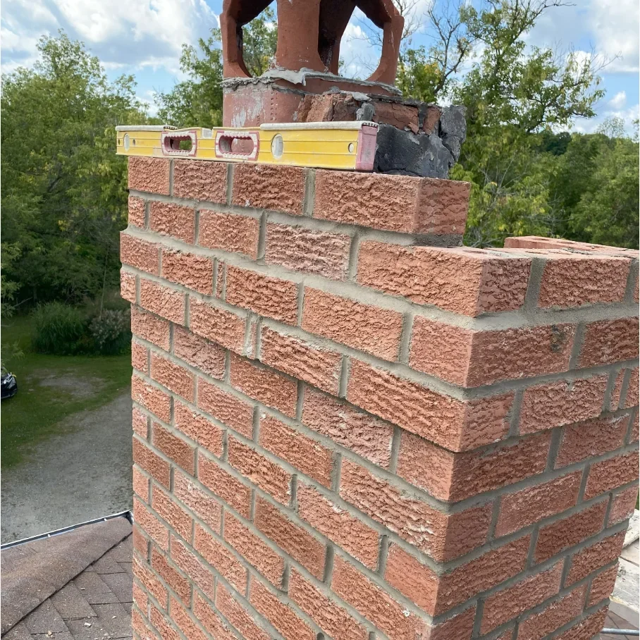 Brick chimney rebuild work in progress with masonry courses visible
