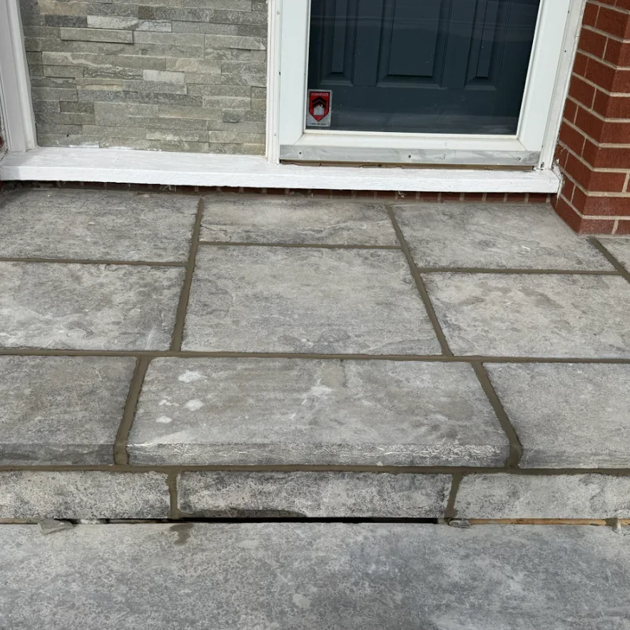 Flagstone entry landing with repointed joints and brick wall context
