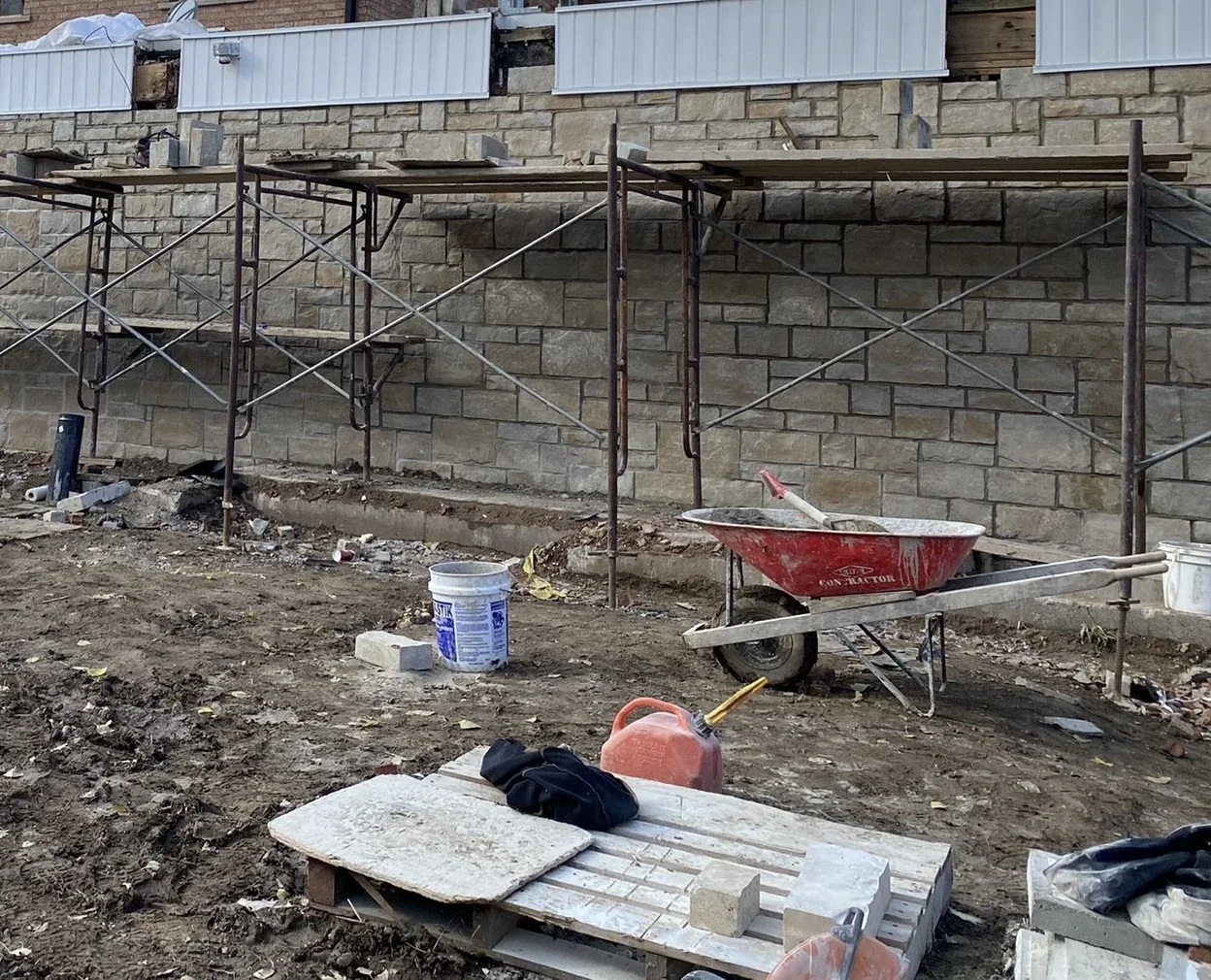Engineered stone veneer and substrate preparation shown with scaffold context.