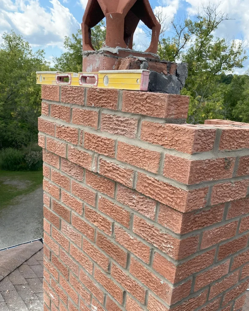 Brick chimney rebuild work in progress with masonry courses visible.