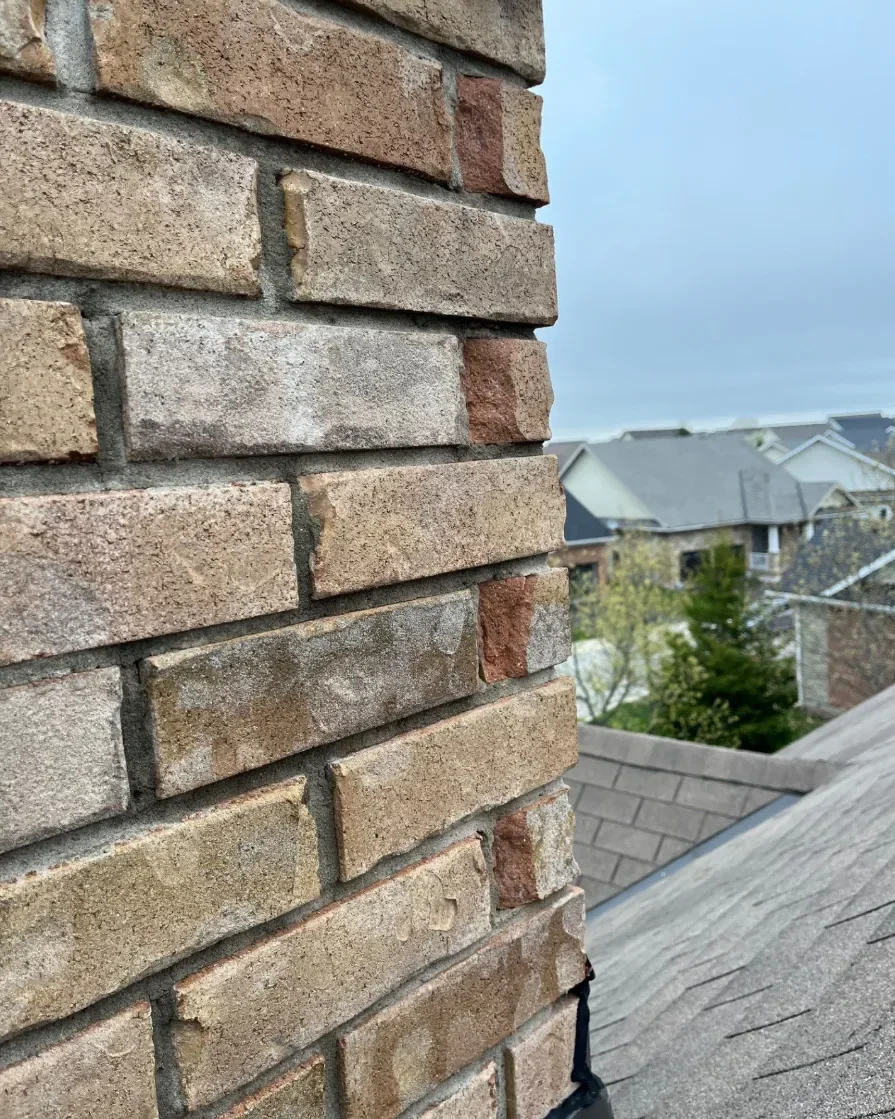 Close view of spalling brick masonry beside a roofline.