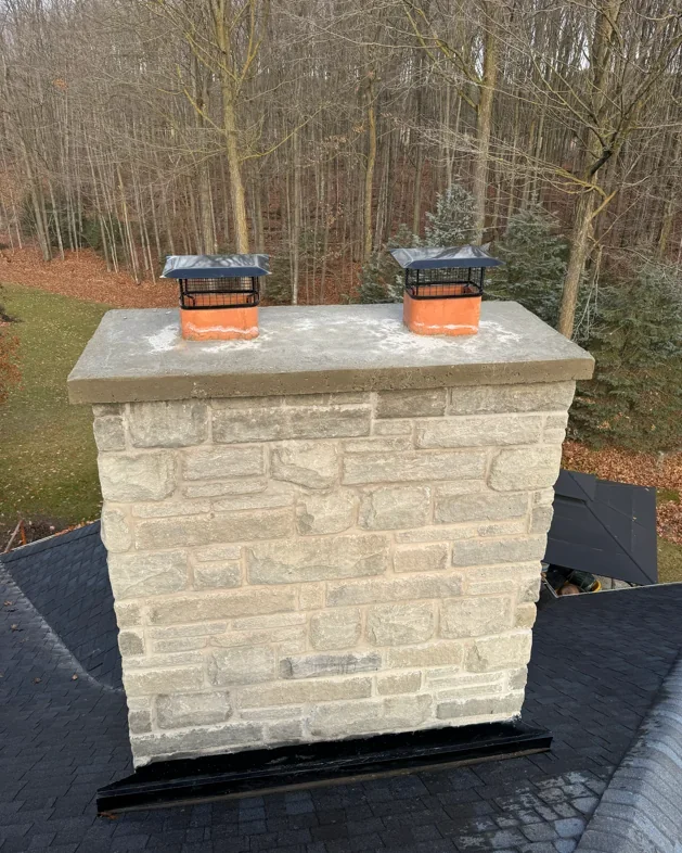 Stone chimney masonry with poured cap and roofline context.