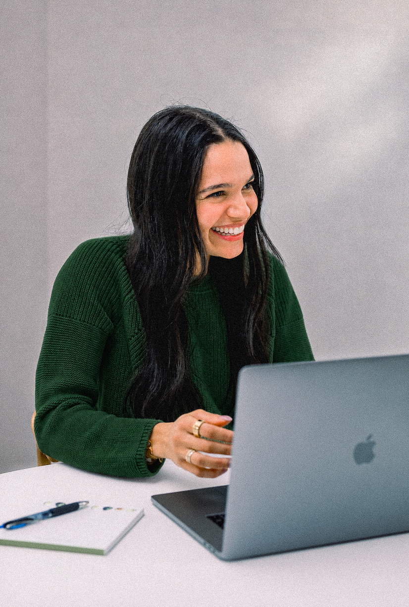 Ziba Klein smiling at her laptop in a green sweater