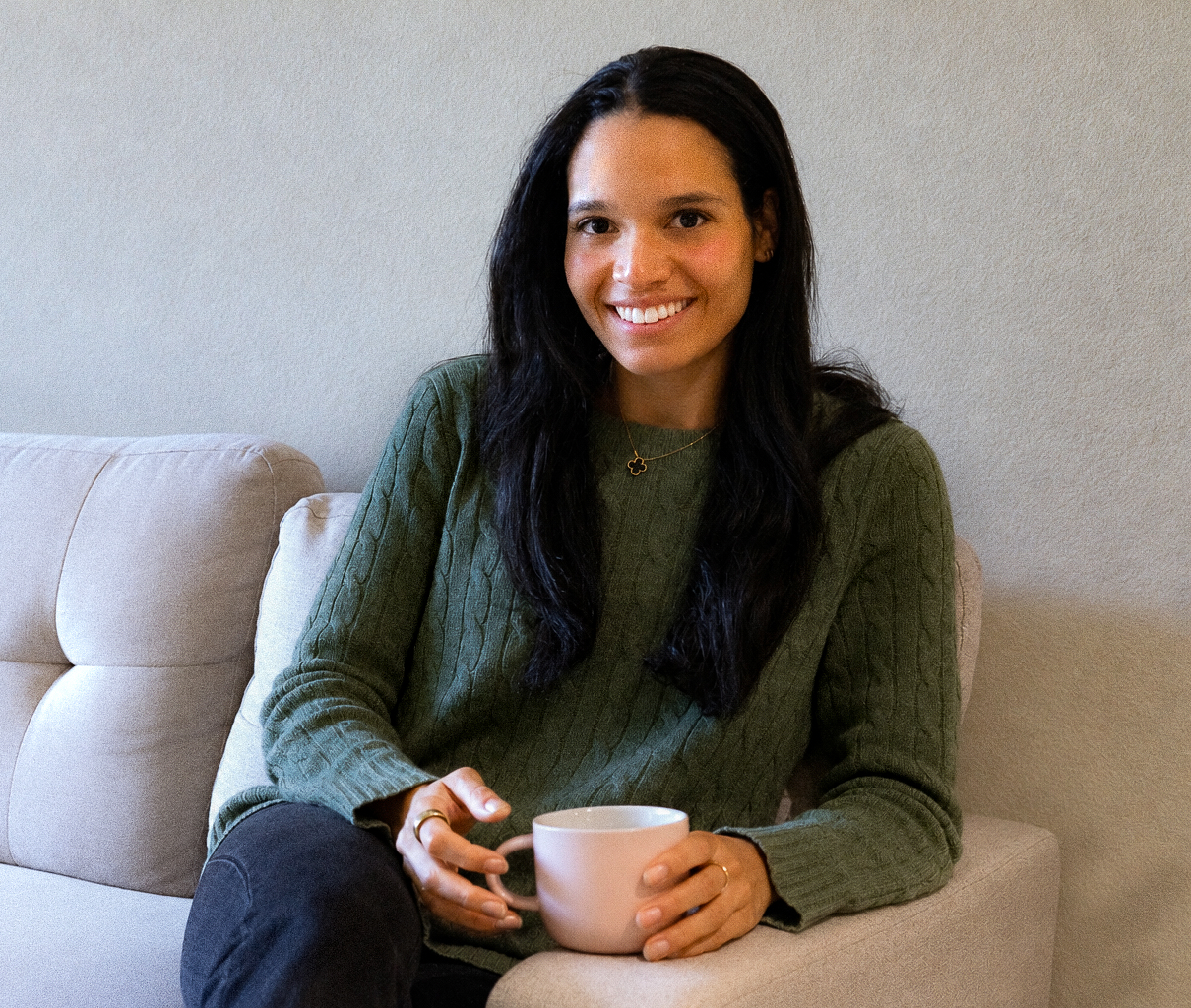 Ziba Klein, Functional Nutritionist, smiling in a green sweater while holding a mug