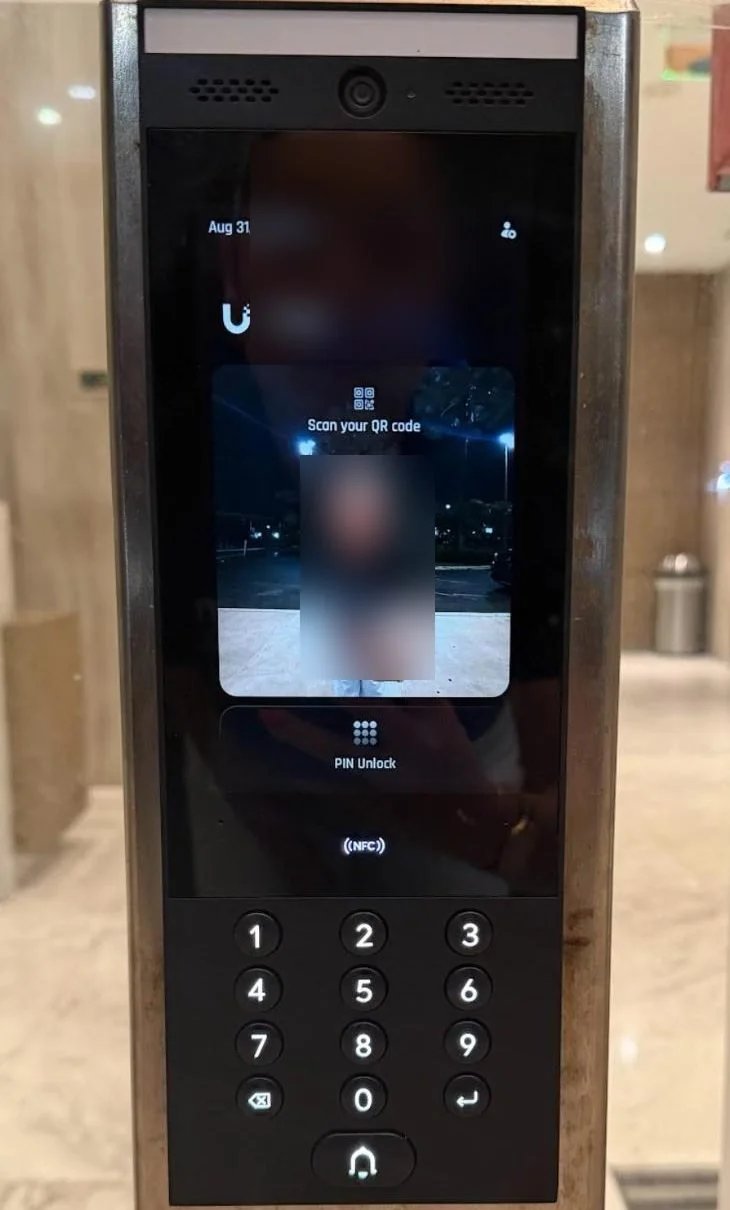 Touchscreen video intercom showing QR code, PIN and NFC entry options above a keypad