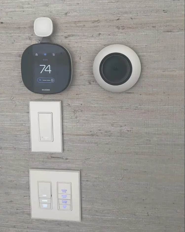 Smart thermostat above engraved lighting and shade keypads in a private residence