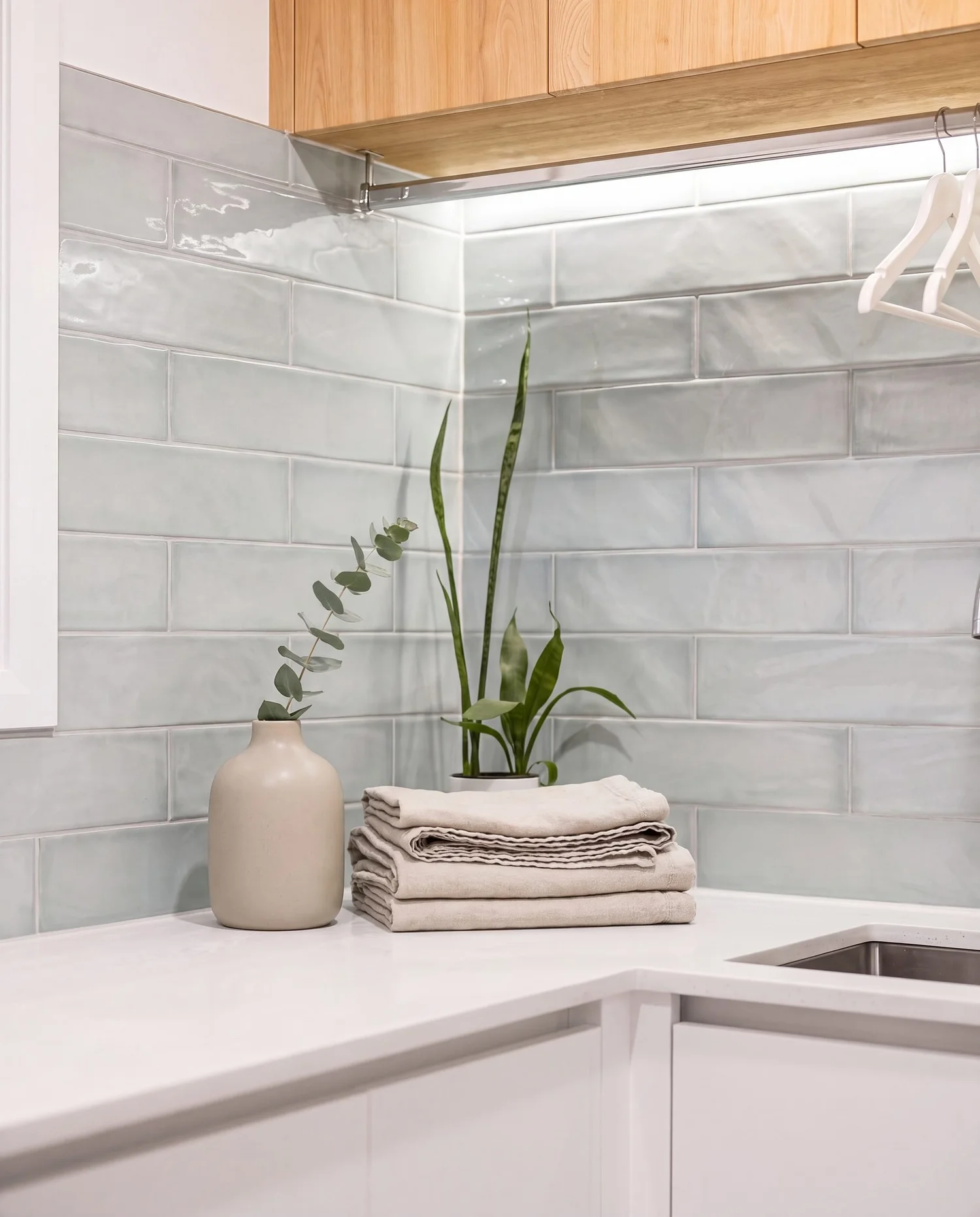 Styled corner of the finished St Heliers laundry with linen, plant and stone benchtop