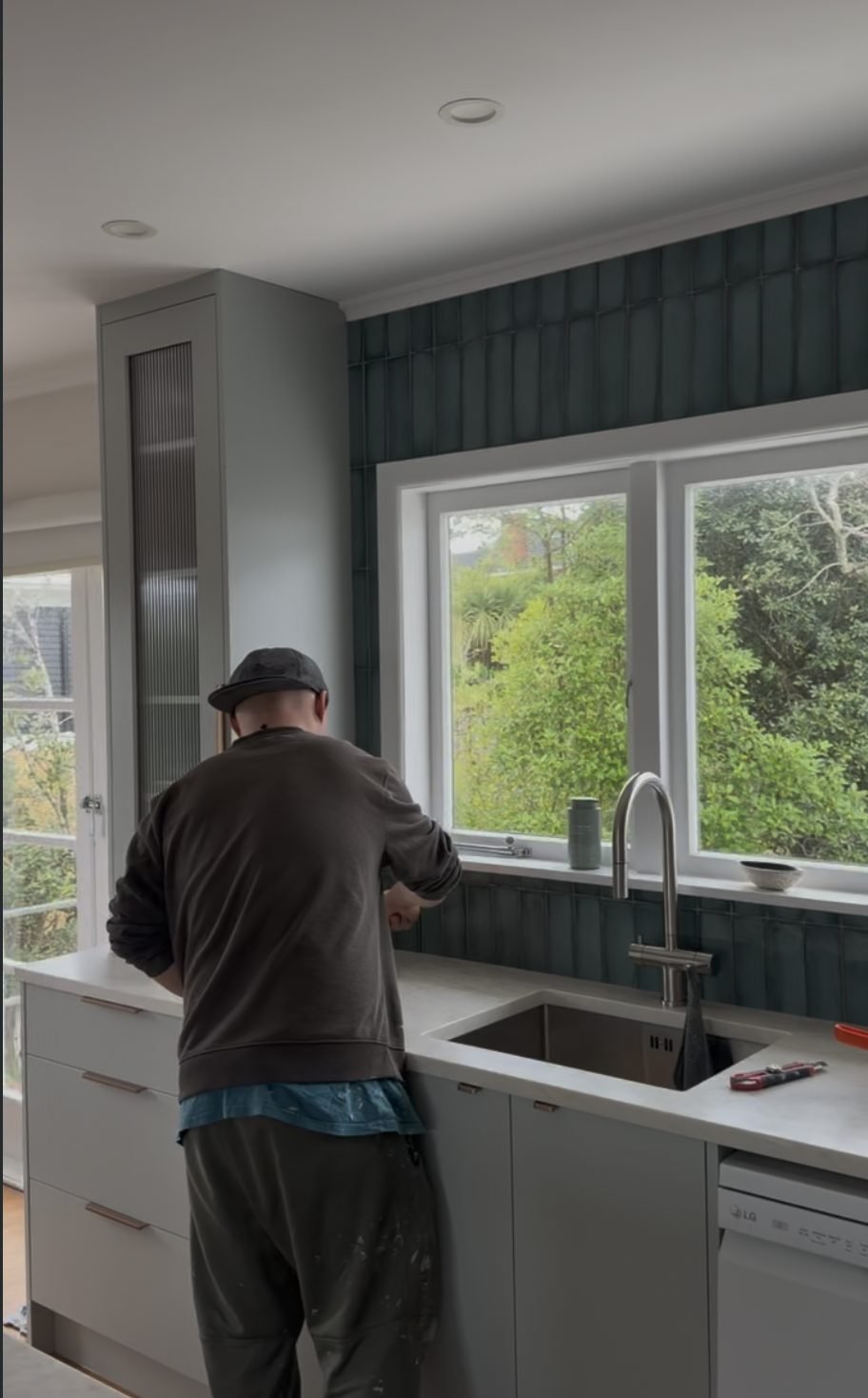 Tap and undermount sink being installed against the green splashback, Merani Street kitchen Belmont