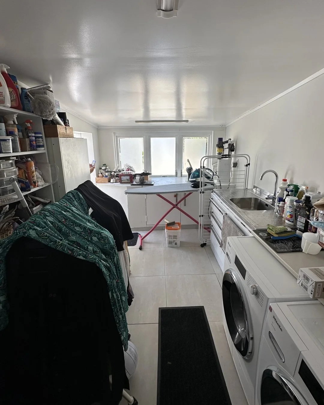 Seymour Street laundry in St Marys Bay before renovation, wire shelving down both walls and clothes on a rack