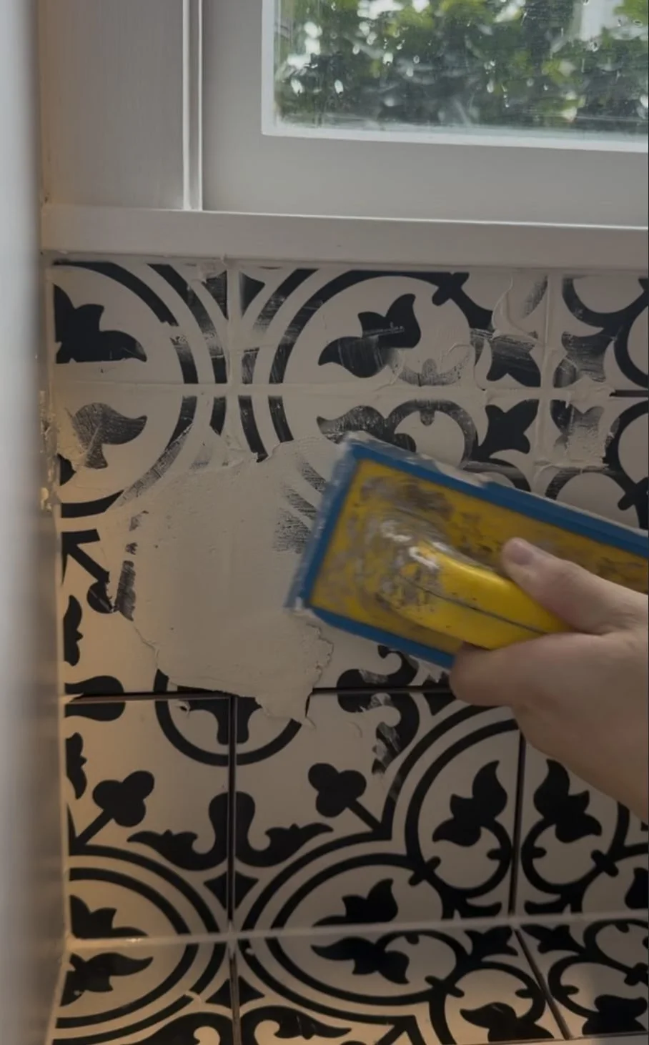 Grout being floated into the black and white encaustic tile in the Belmont laundry