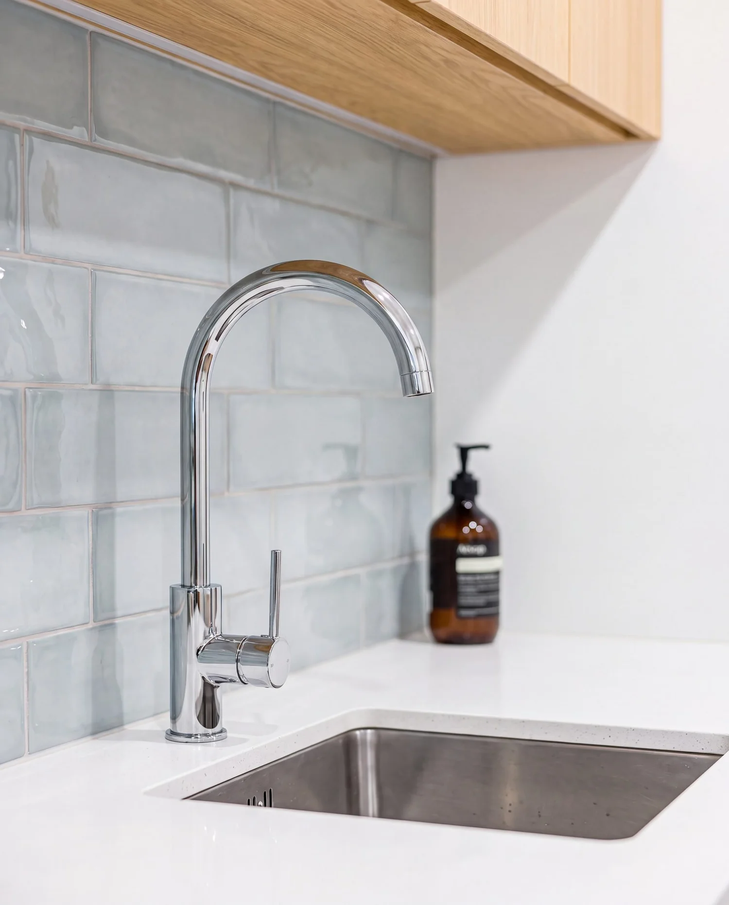 Slim chrome pin-lever gooseneck mixer over a stainless undermount sink, Rarangi Road laundry