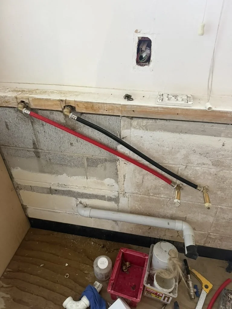 Hot and cold flexible lines and waste pipe roughed in against the block wall, Merani Street