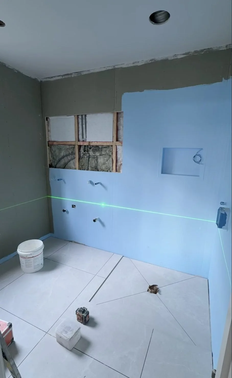 Large-format porcelain set out on a green laser line with levelling clips, Churchouse Road Greenhithe
