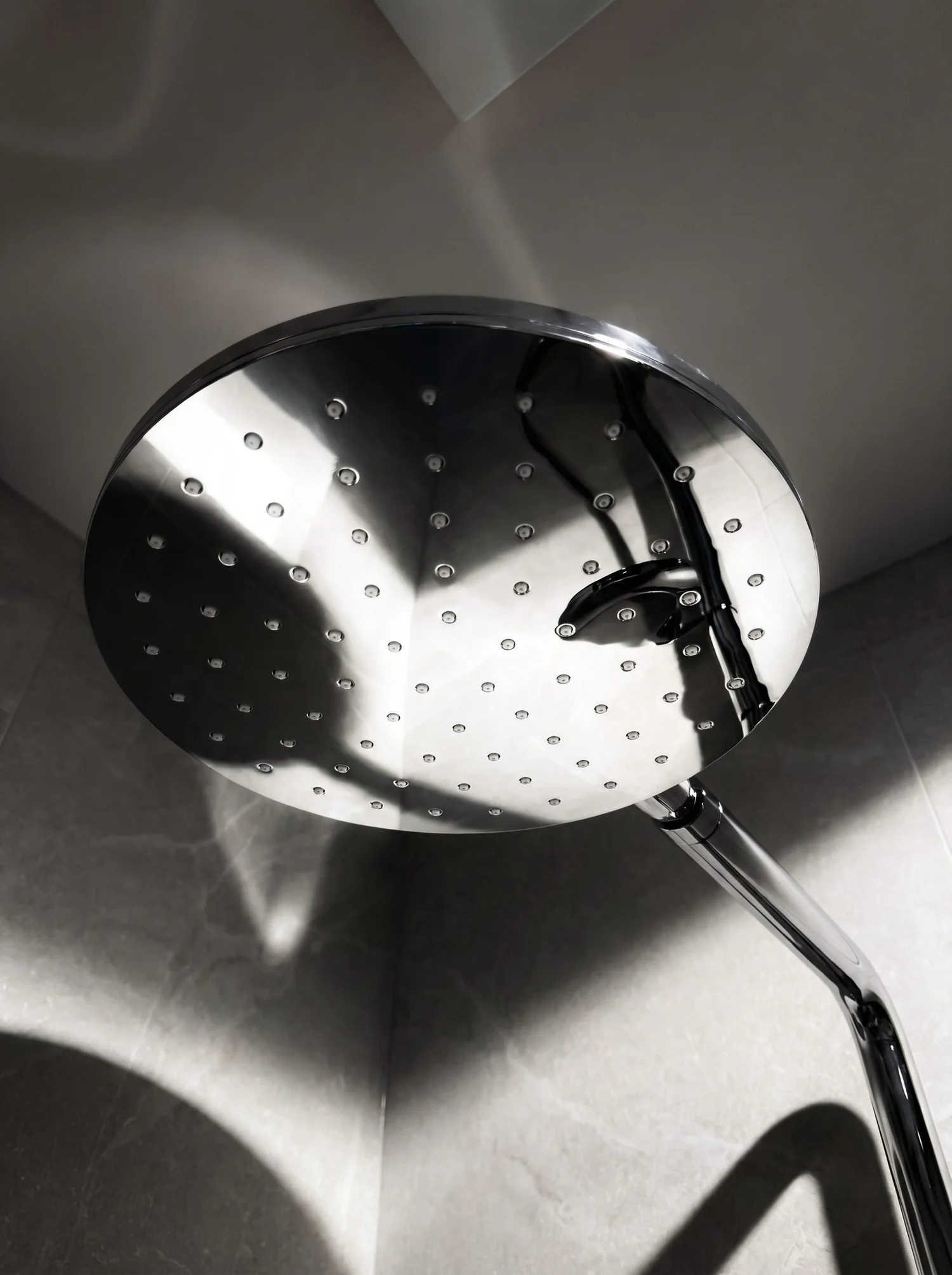 Chrome rain shower head against large-format porcelain in the Churchouse Road master bathroom, Greenhithe