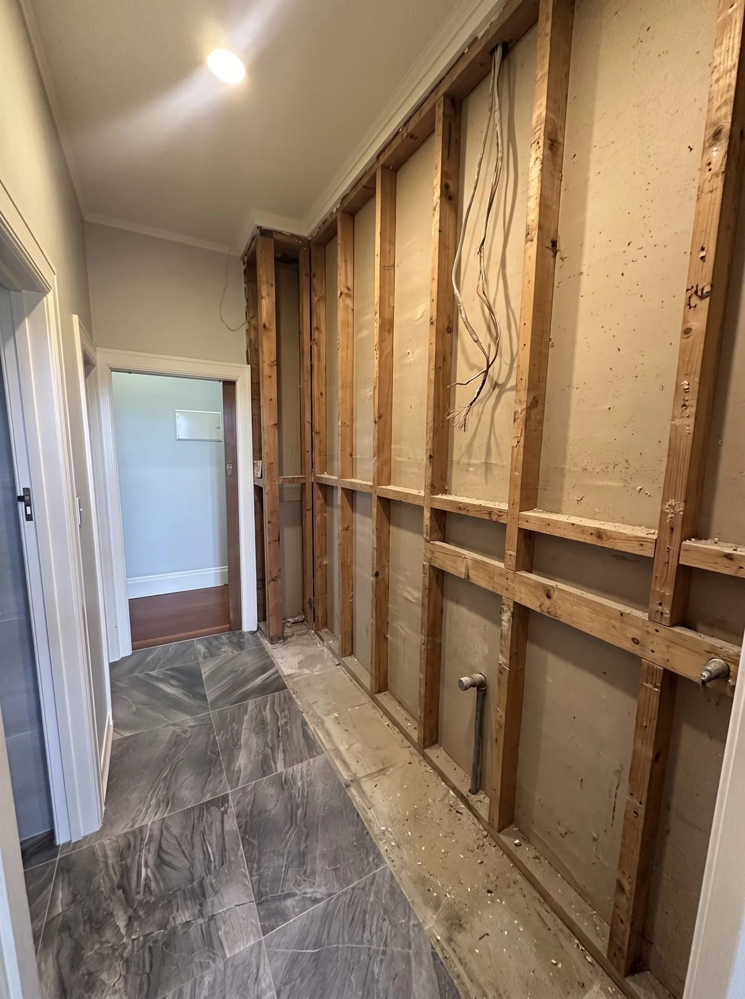 Bayswater laundry stripped back to bare timber studs during renovation, original tiled floor retained