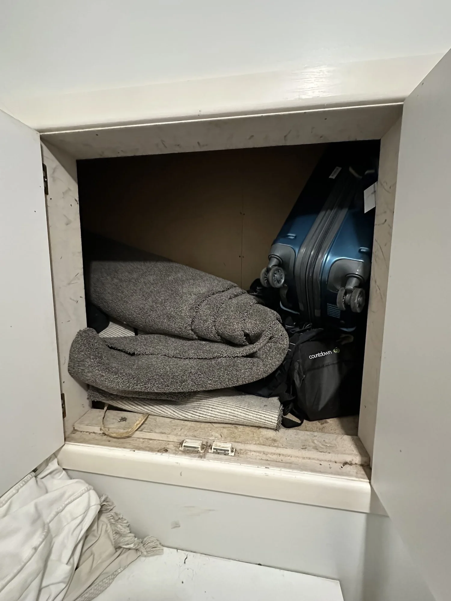 The wall hatch stuffed with a suitcase, blankets and rolled carpet before the Rarangi Road laundry renovation