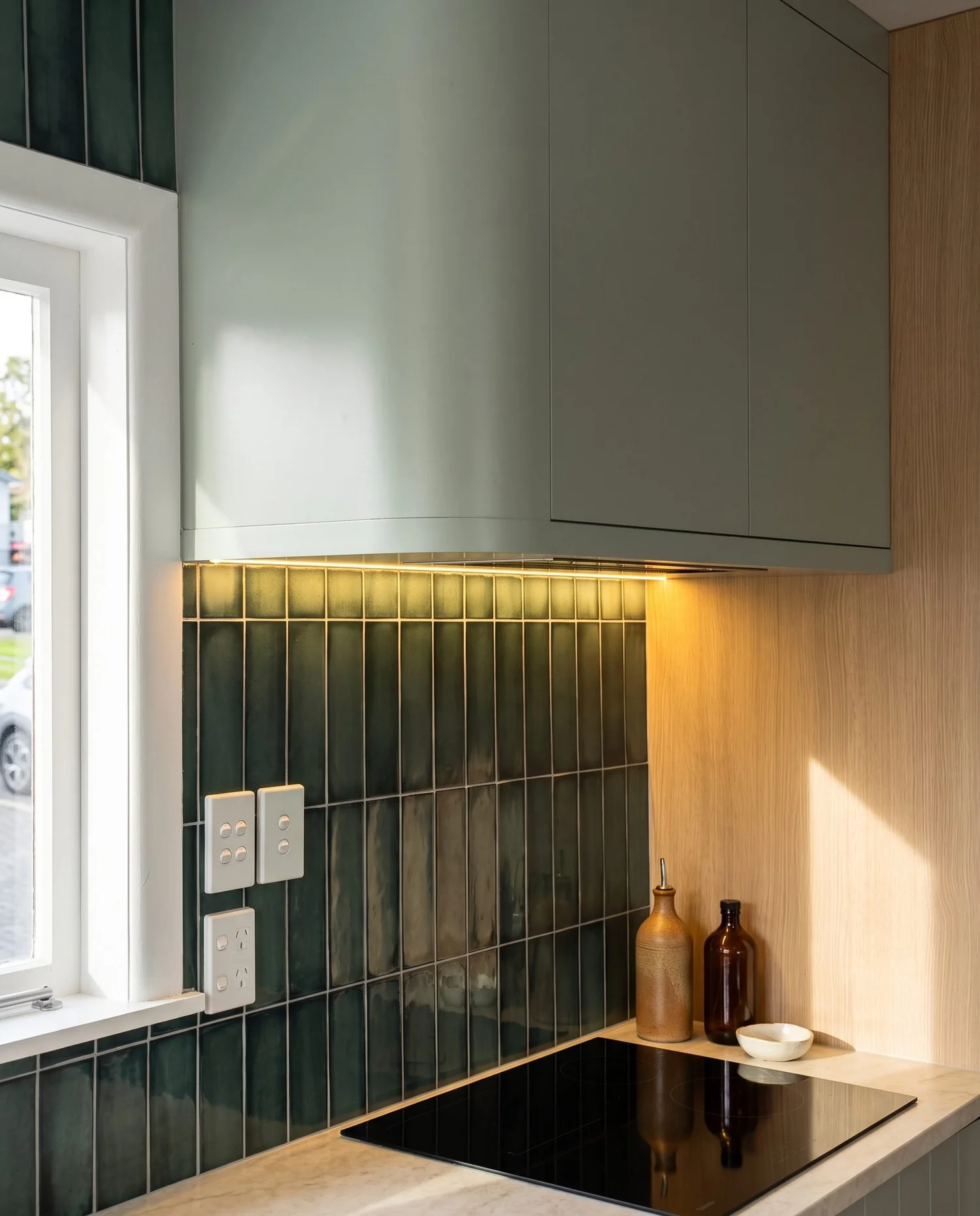 Black glass cooktop and rangehood against the green vertical tile, Belmont kitchen renovation