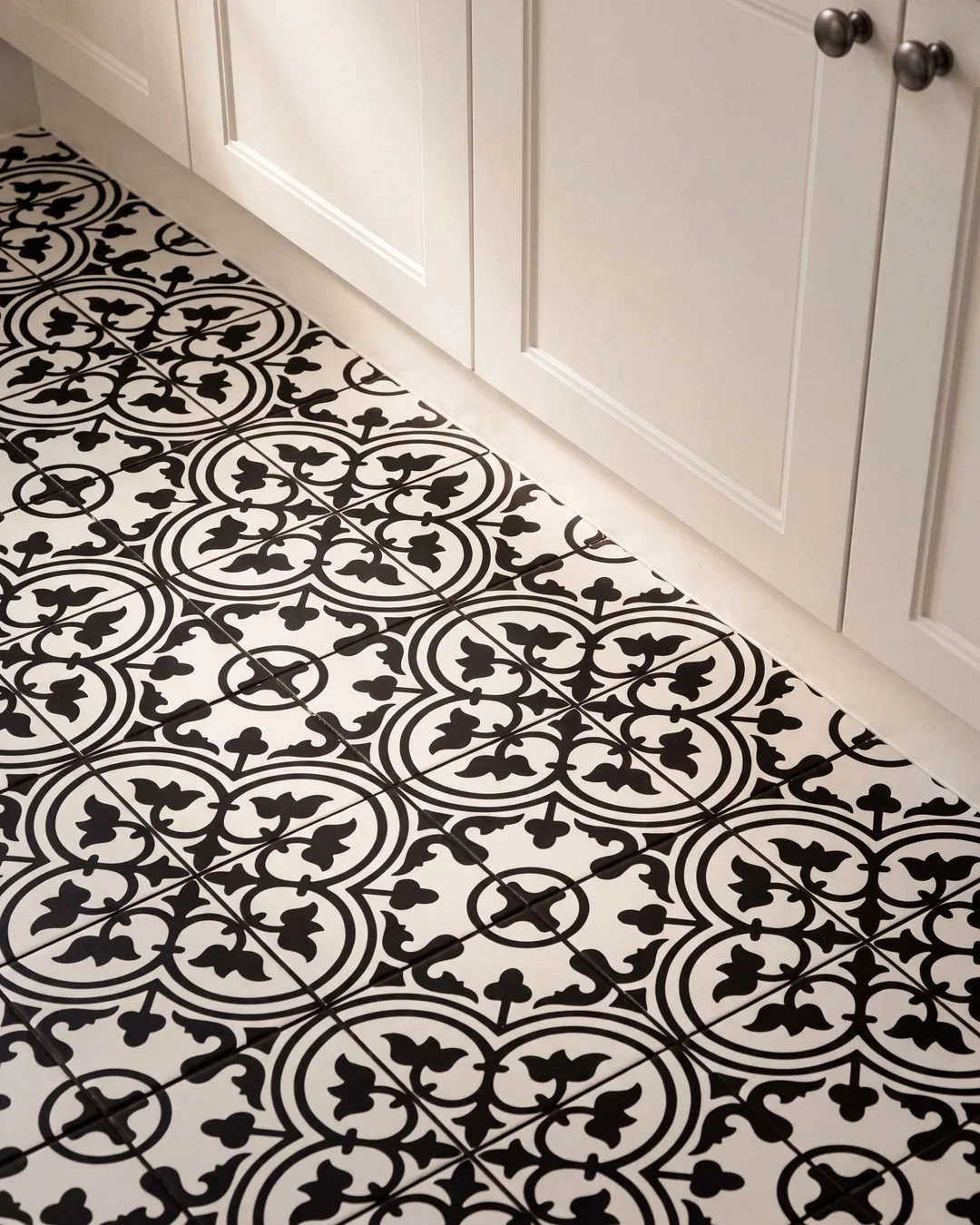Encaustic pattern floor tile meeting white skirting and shaker cabinetry, St Marys Bay laundry