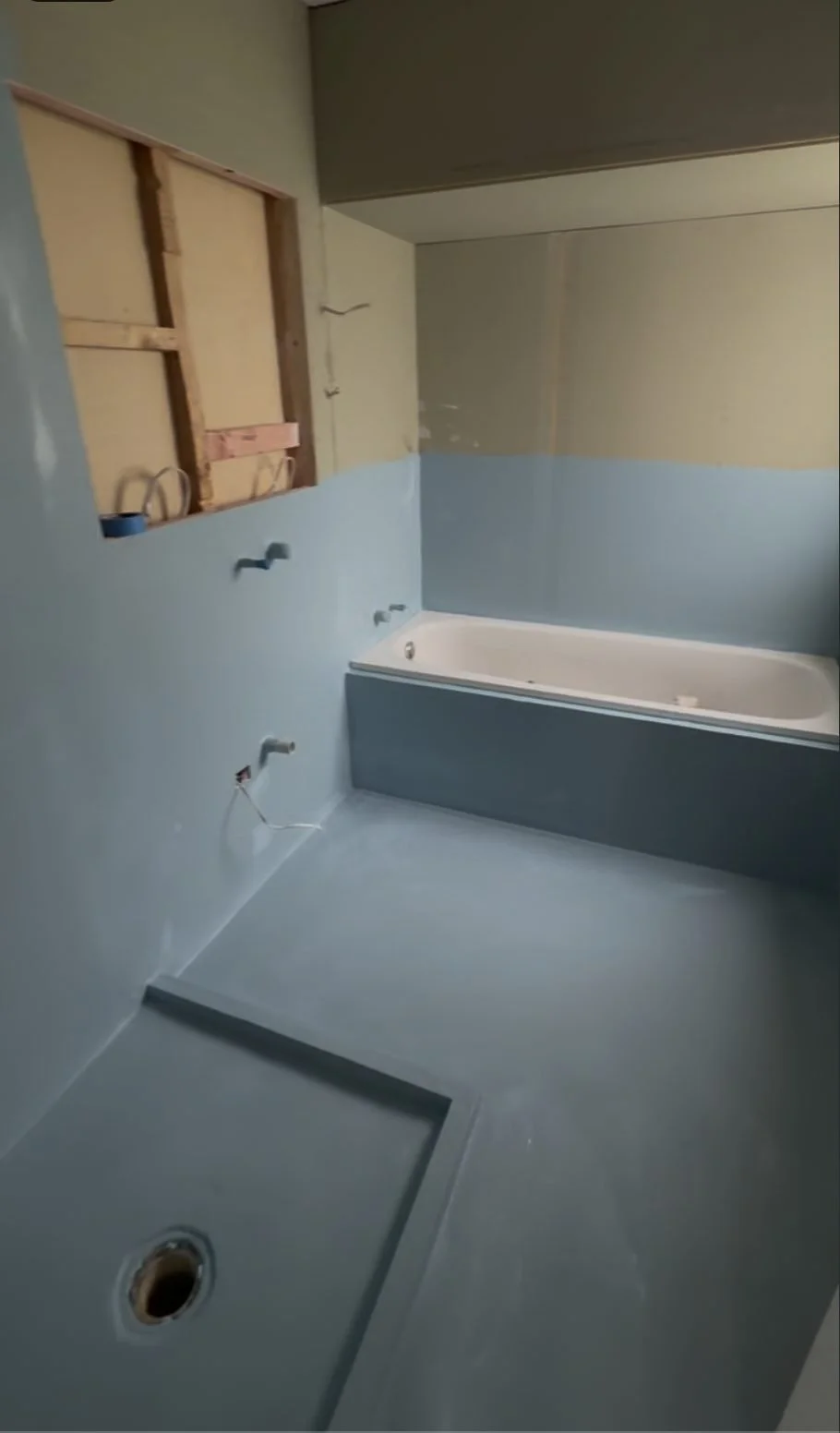 Waterproofing membrane applied to the walls and floor of the Greenhithe family bathroom, with the new bath and shower hob in