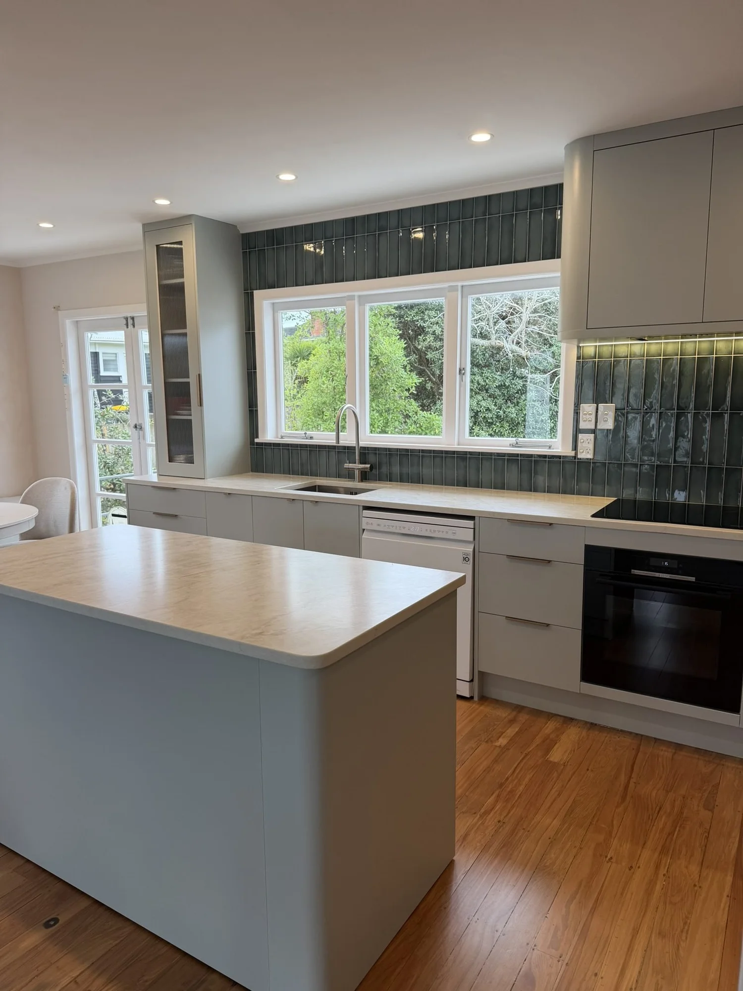 Finished kitchen renovation in Belmont with sage cabinetry, stone island and green splashback