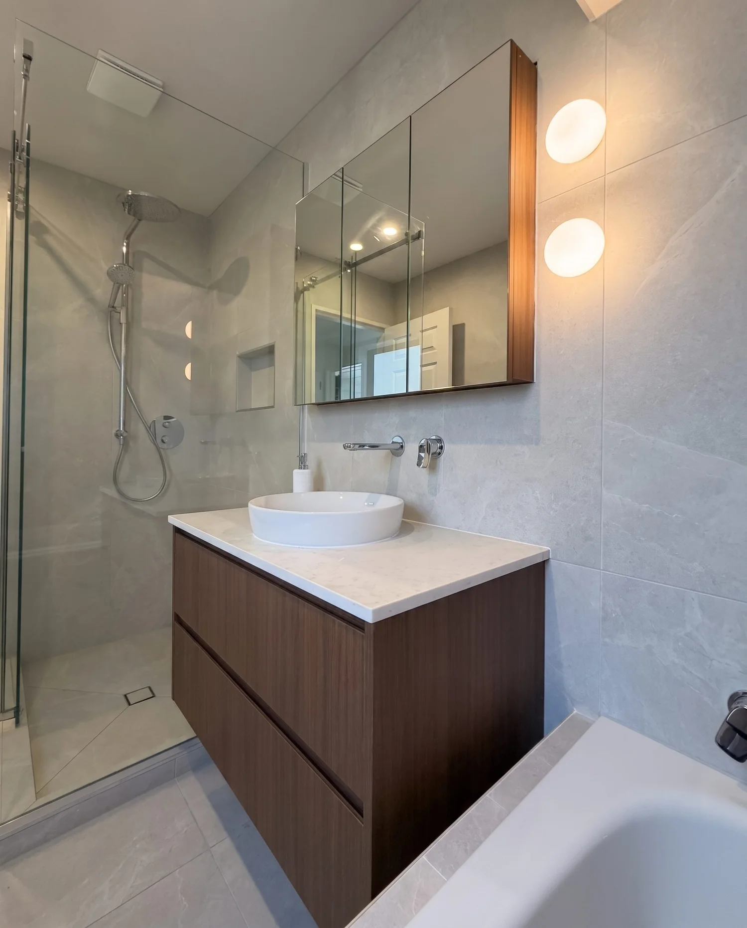 Walnut floating vanity with the frameless glass shower behind it in the Greenhithe family bathroom