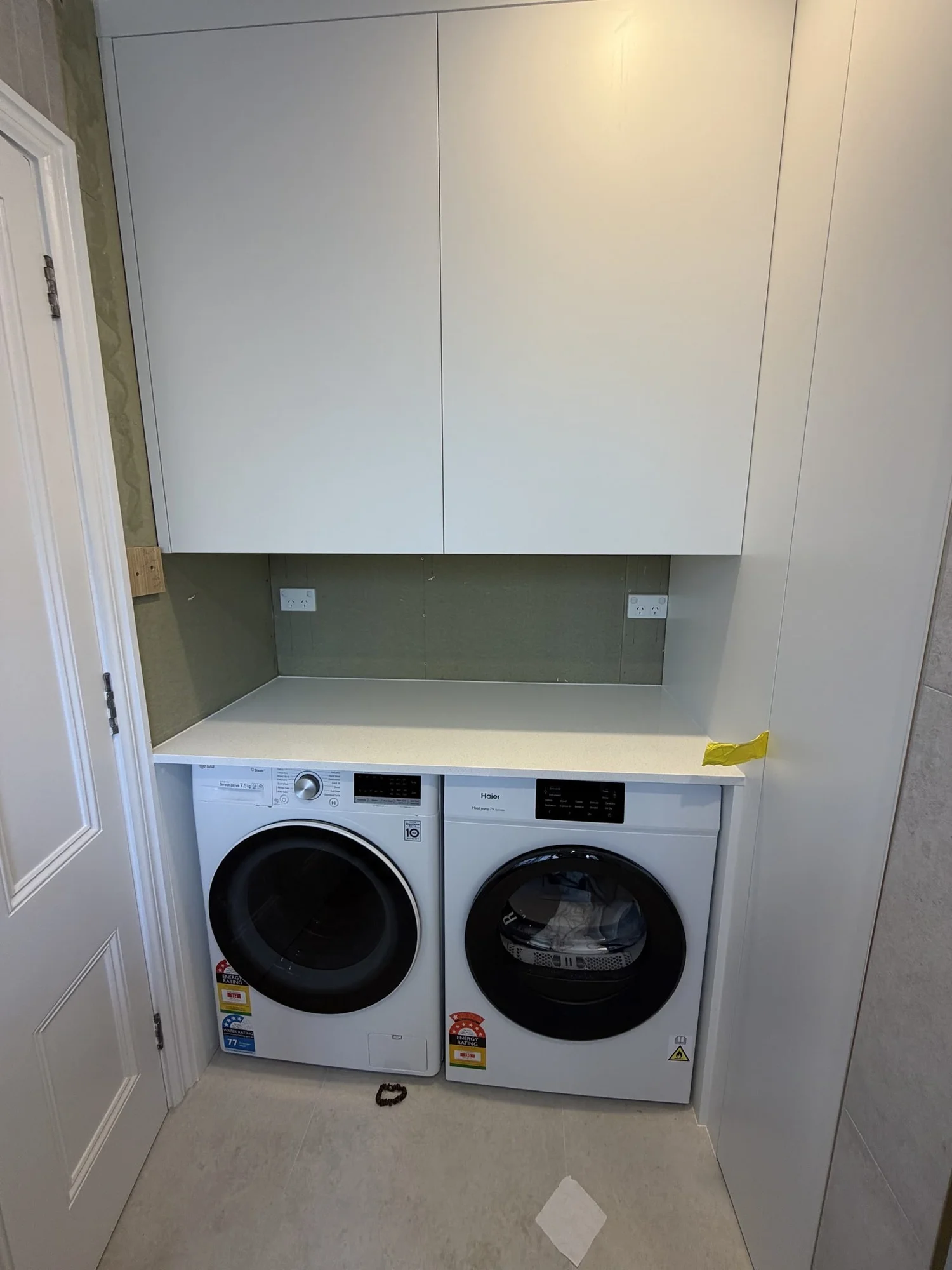 Built-in laundry with washer and dryer under a stone benchtop and overhead cabinets, Garfield Street Parnell