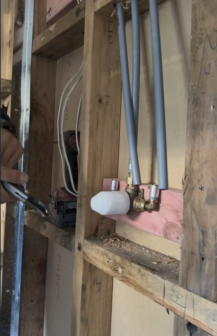 Plumbing rough-in inside the wall cavity of the Belmont laundry bathroom renovation
