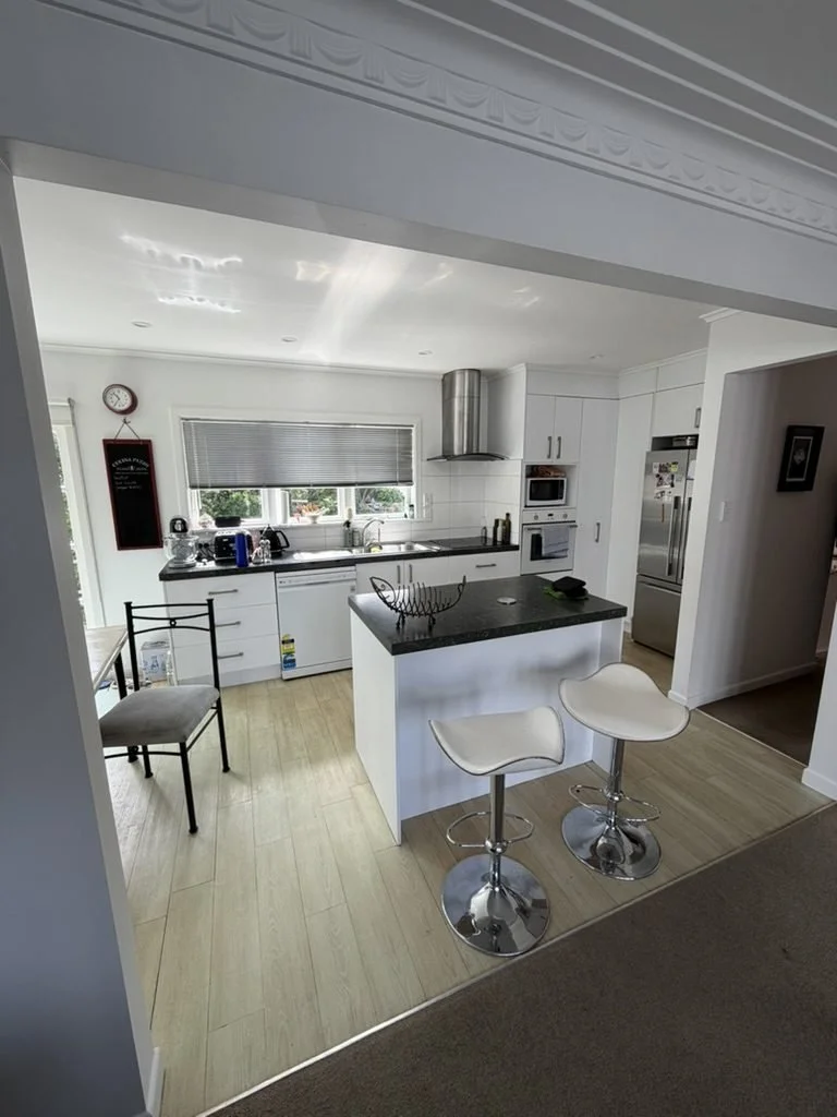 Old Belmont kitchen before renovation showing the island and dark benchtop from the living side