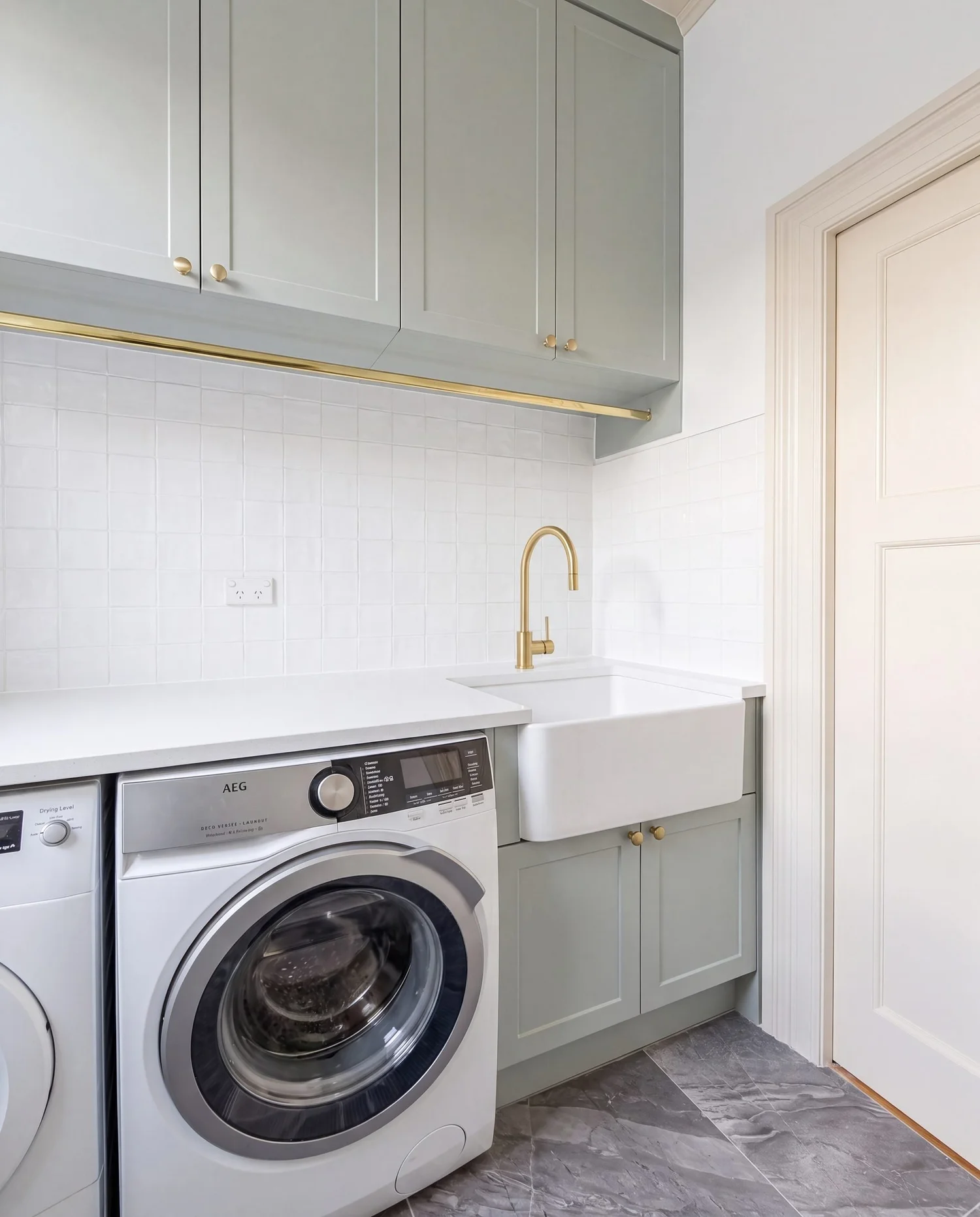 Washer and dryer side by side in the laundry appliance nook under the stone bench