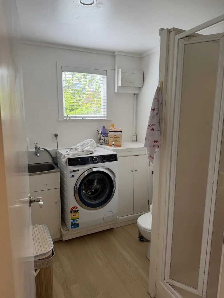 The old framed shower box and toilet in the combined Belmont laundry bathroom before renovation