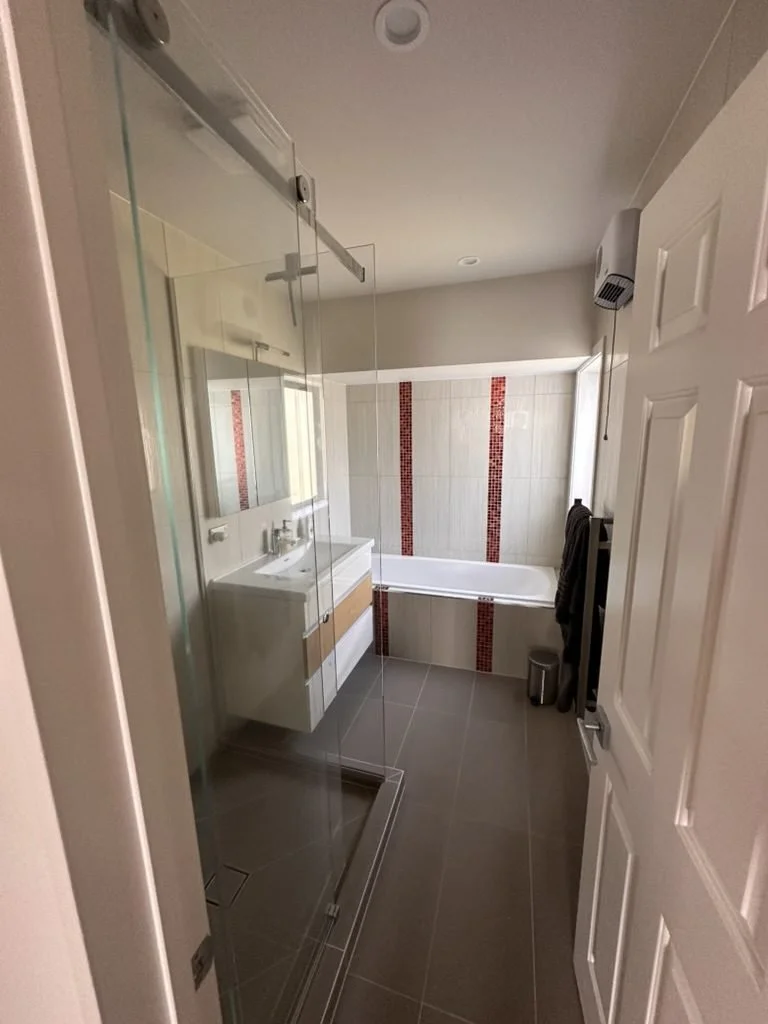 The old Greenhithe family bathroom before renovation seen from the door, showing the shower, vanity and bath