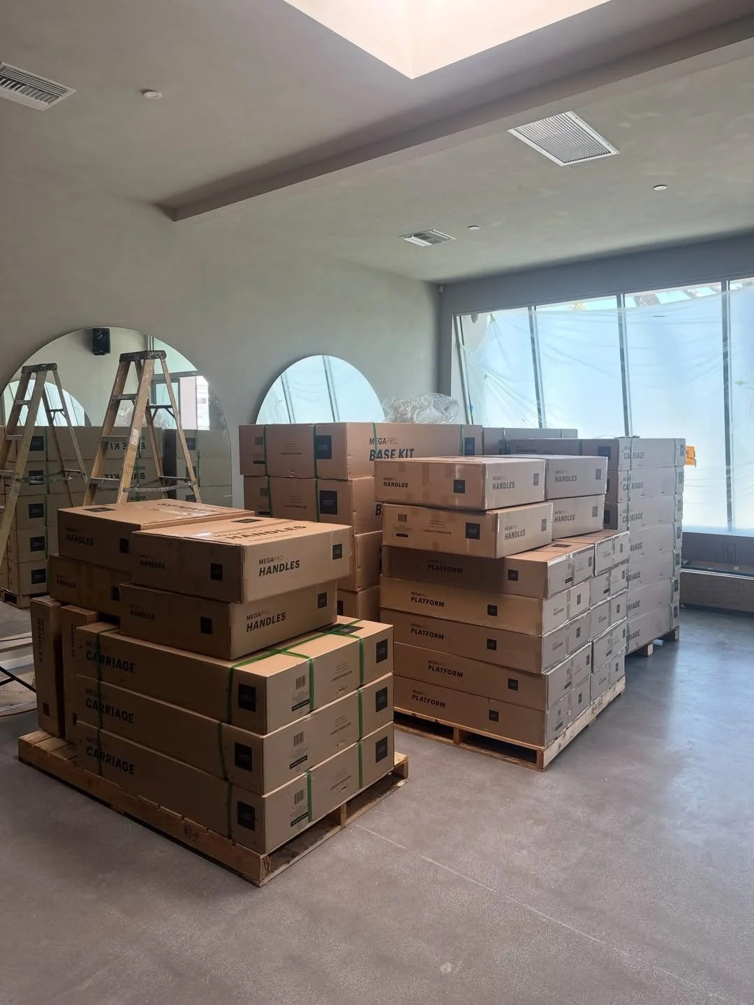Pallets of boxed Lagree machines in the half built room