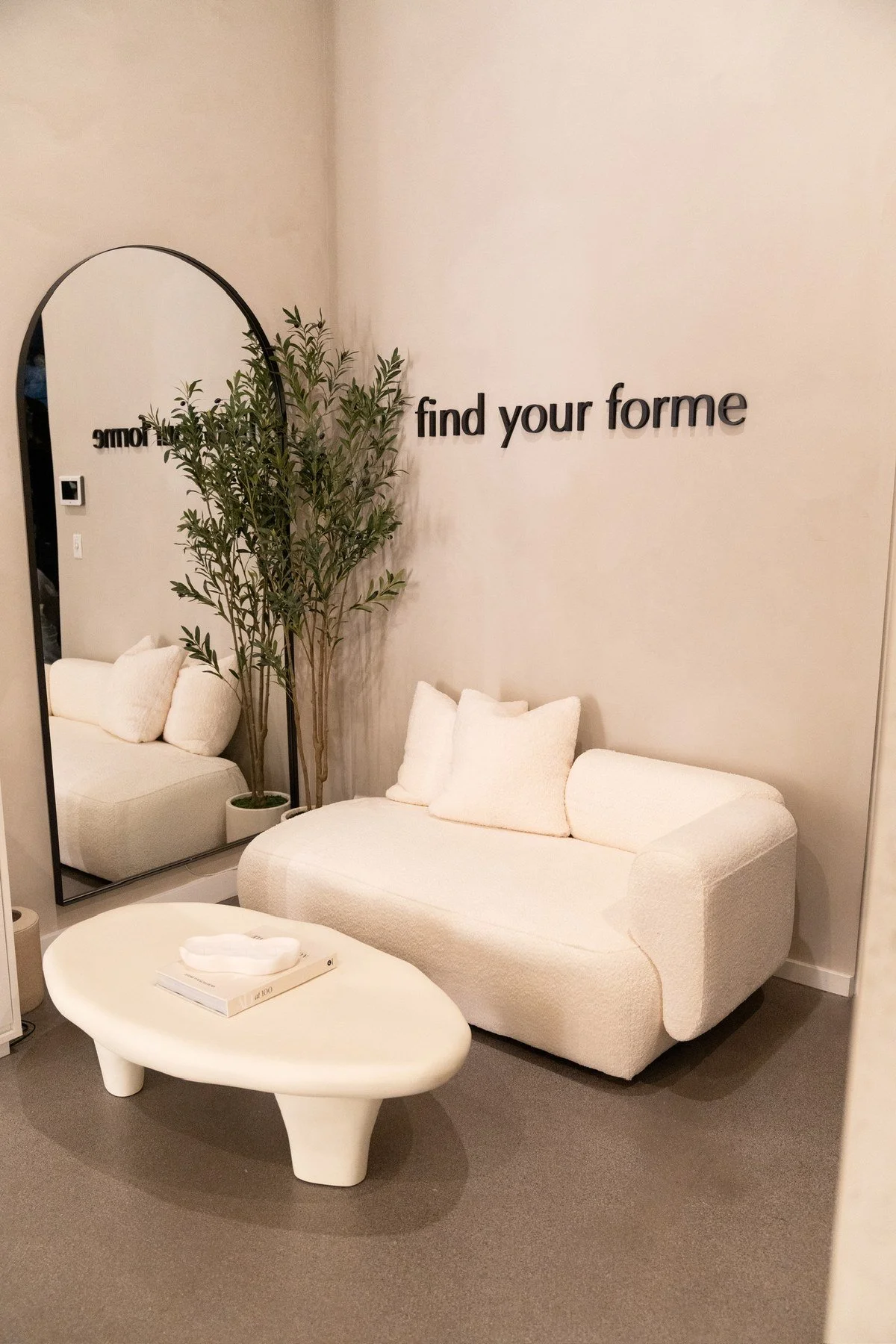 The lounge: a white sofa under the find your forme wall, beside an arched mirror