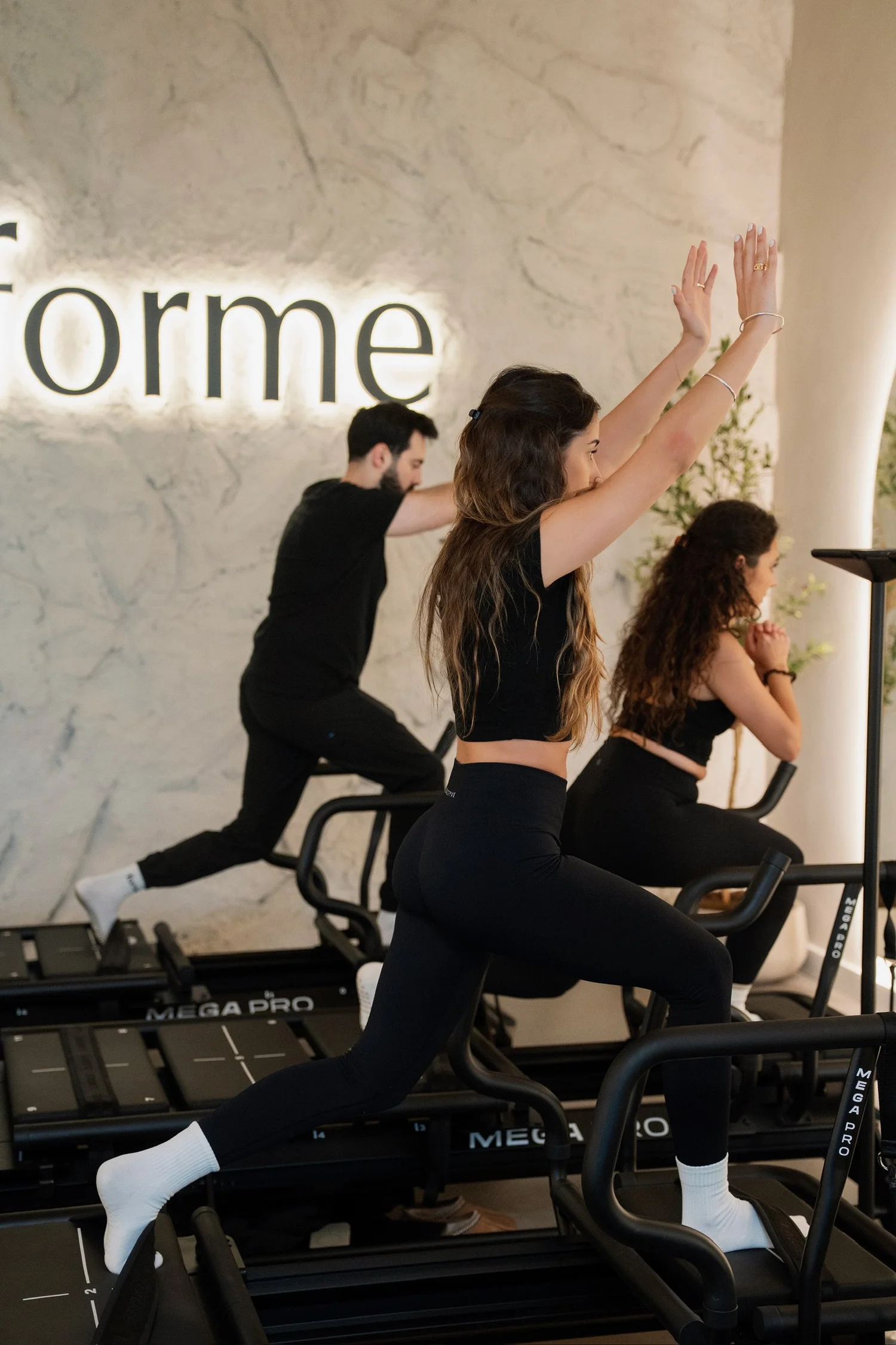 Lagree instructor candidates lunging on Mega Pro machines under the Forme sign