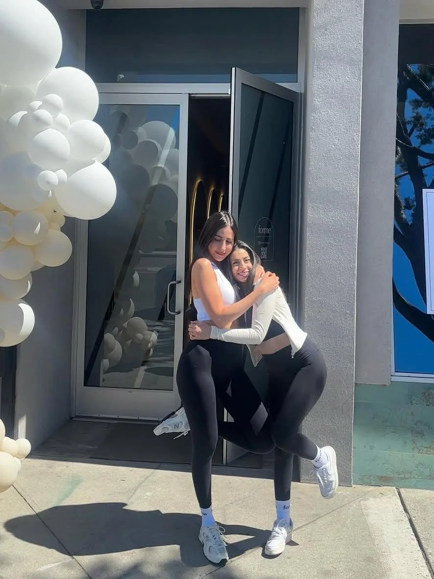 A hug at the studio door beside the white balloons on opening day