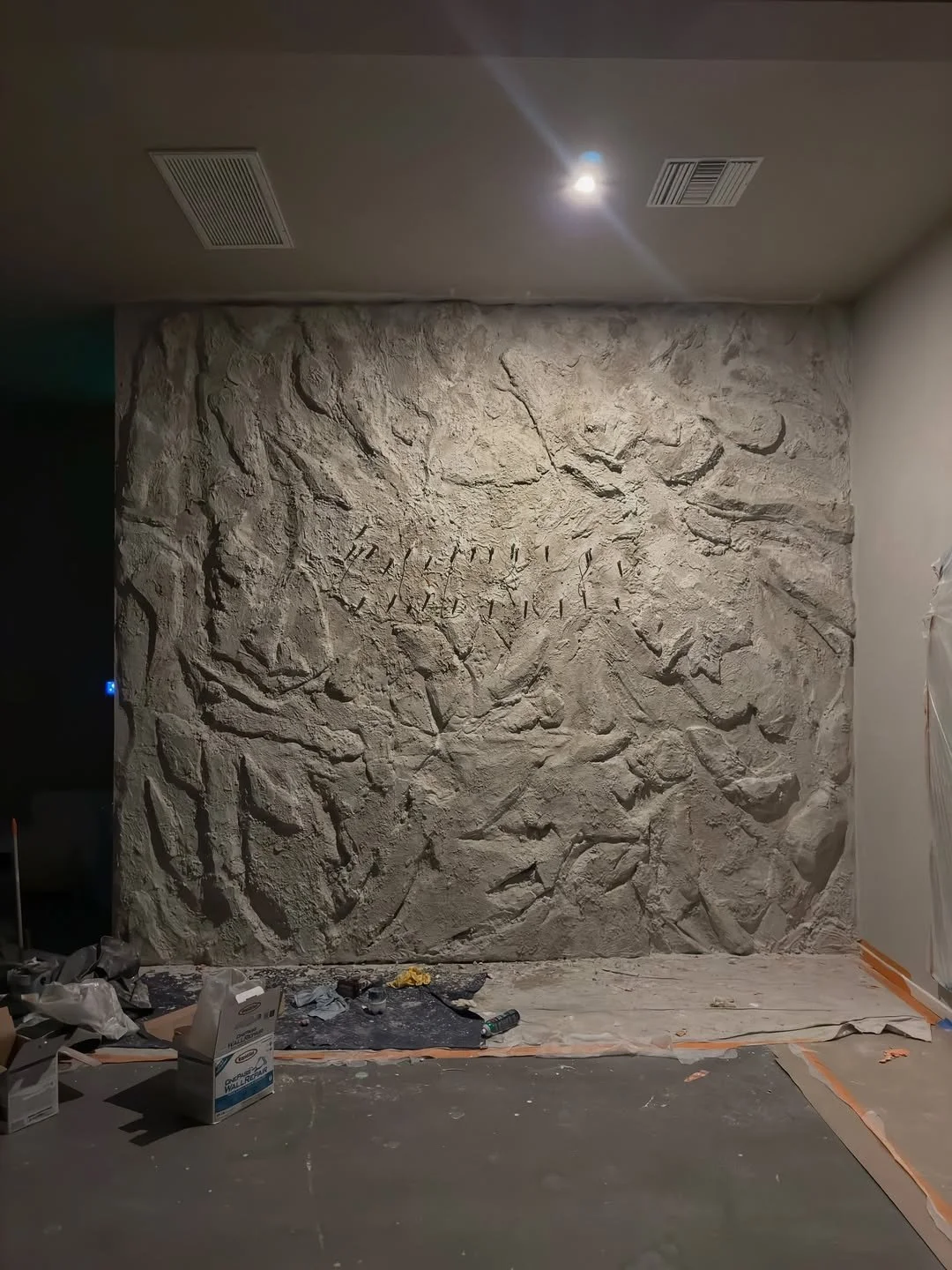 The textured plaster wall going up behind the future forme sign