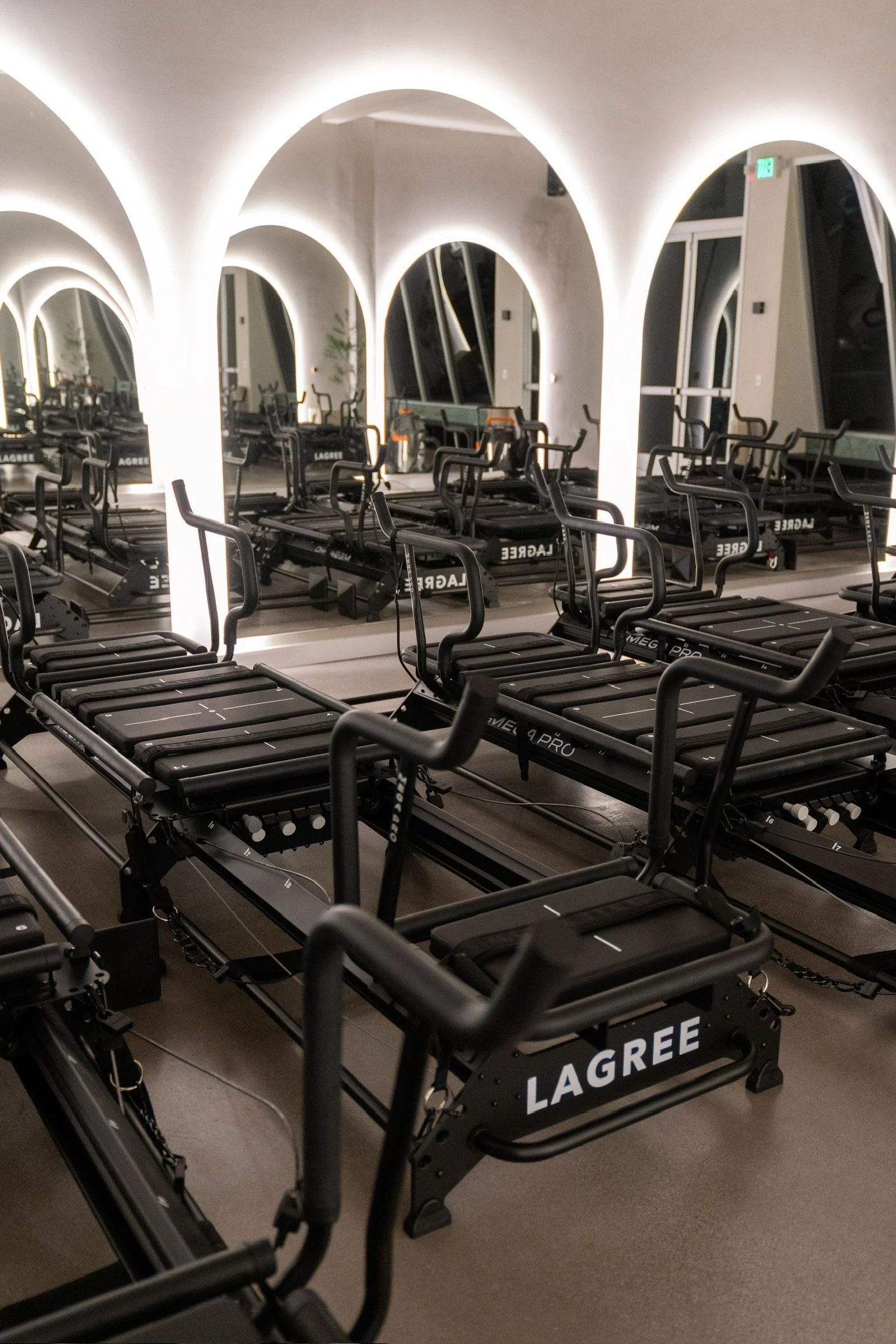Rows of Lagree Mega Pro machines in front of mirrors, under backlit arches at Forme Burbank