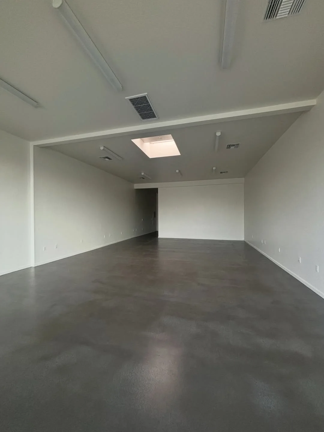 The empty unit on Magnolia Blvd: bare white walls, a concrete floor and a skylight