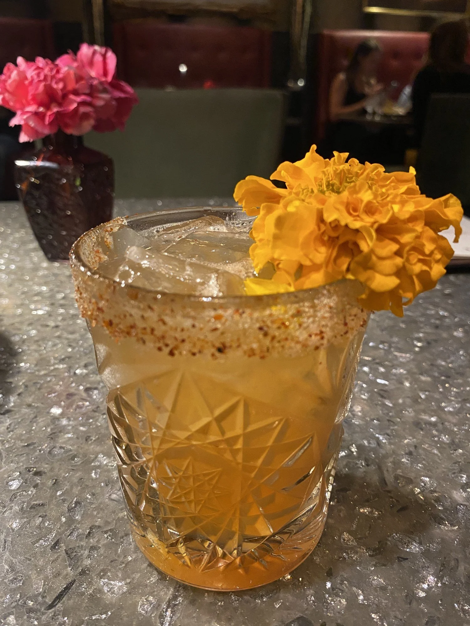 A cocktail with a chili salt rim and marigold at Tac/Quila
