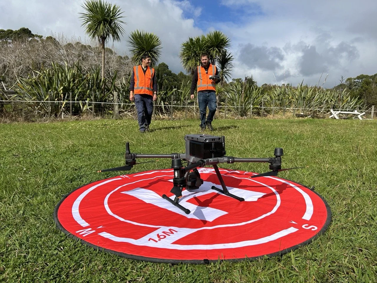 Envivo team members with a survey drone on a red landing pad outdoors.