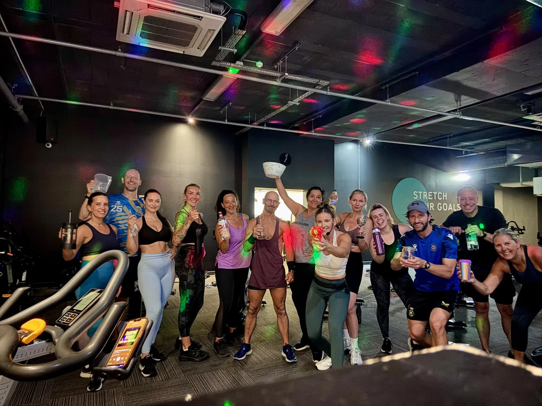 A group photo in the spin studio under colourful lights