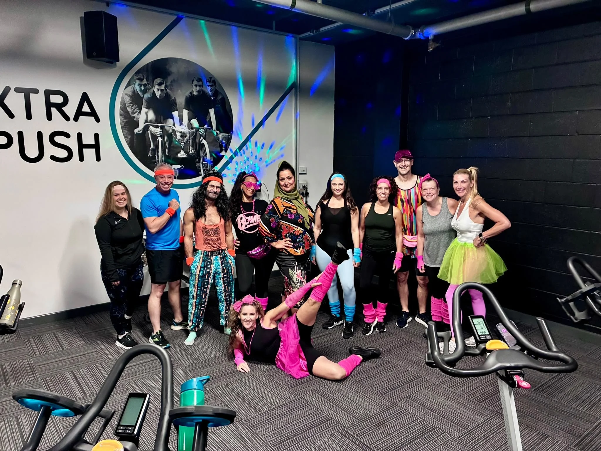 Class members in colourful outfits posing beside the bikes