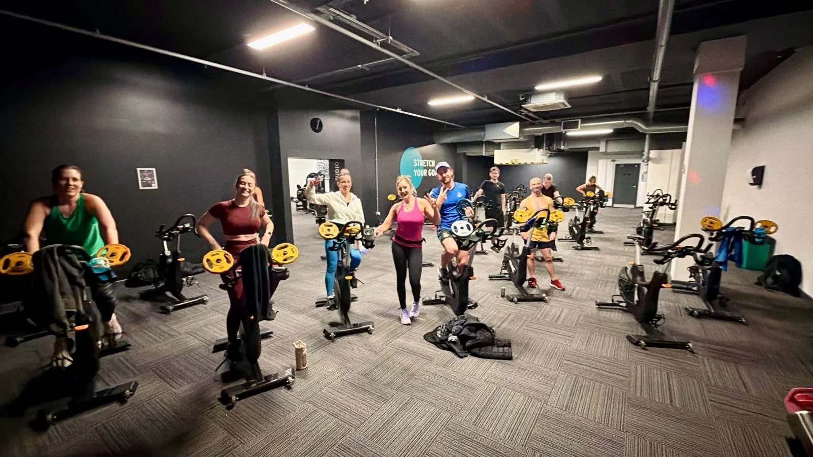 Participants holding small plates beside spin bikes during a class