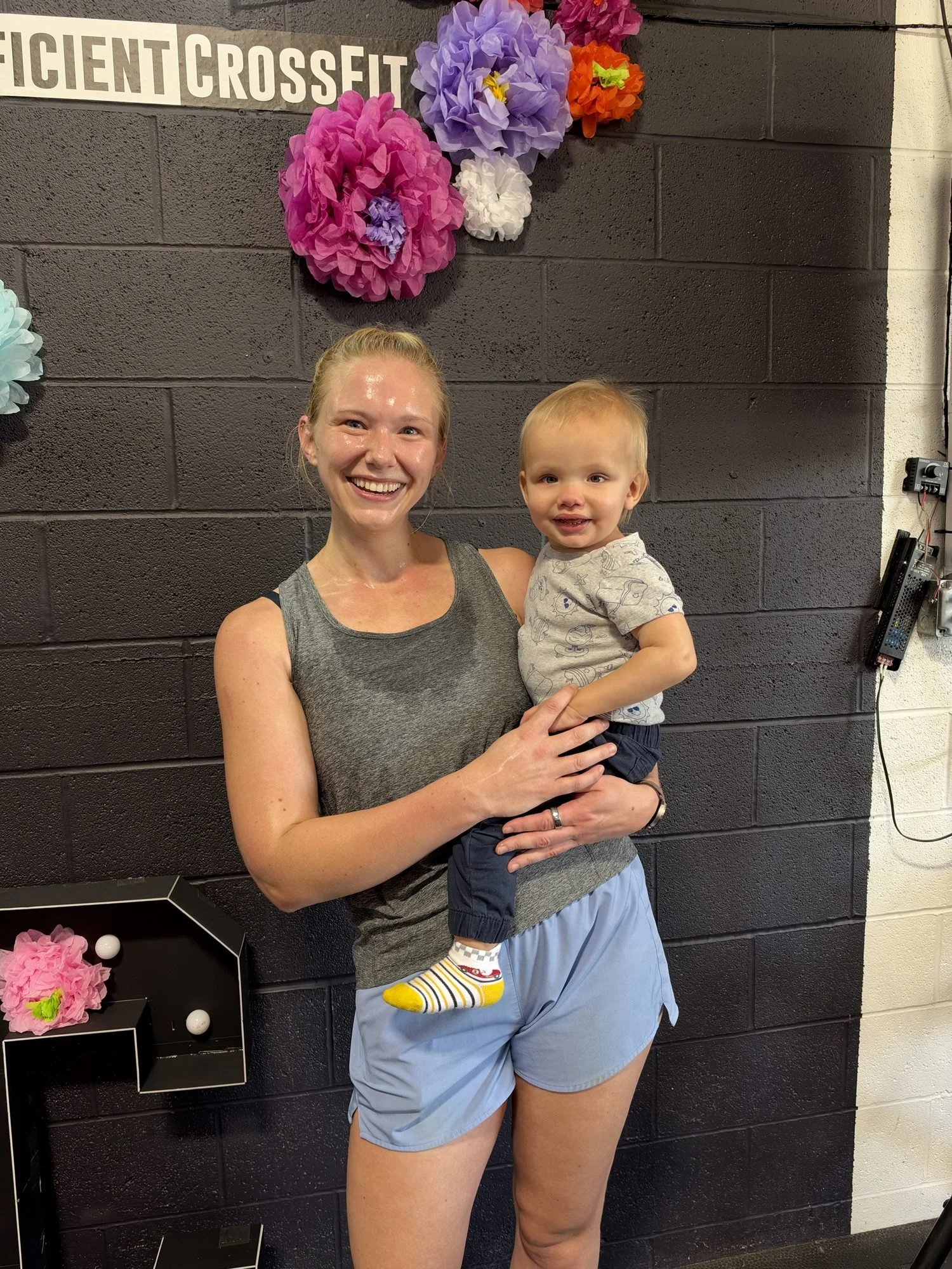 A Coefficient member holding her toddler in the gym after class