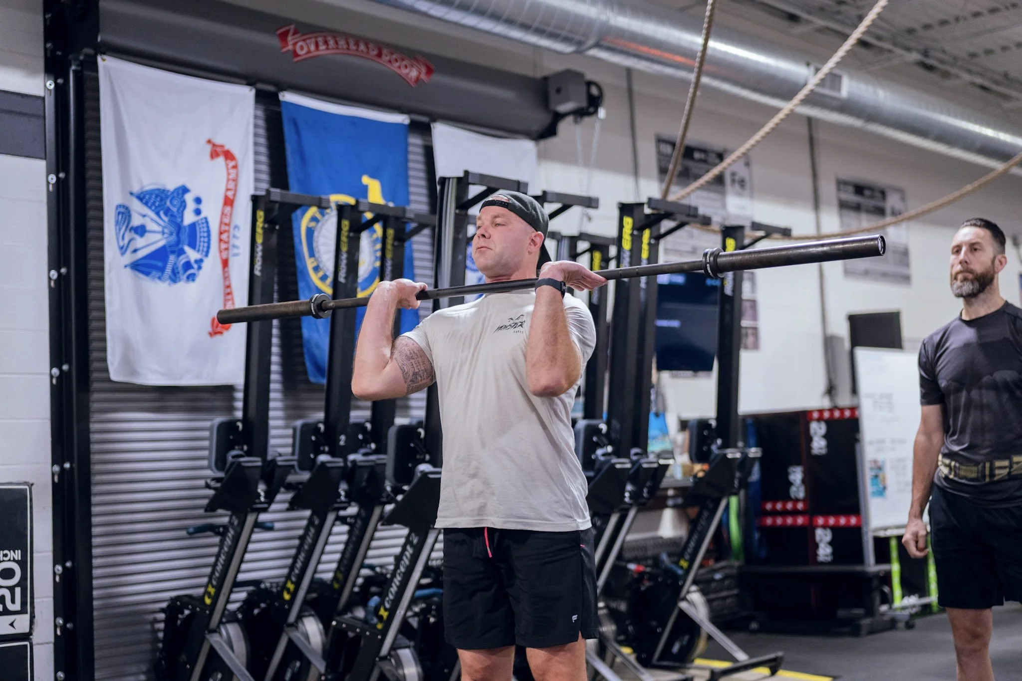 A member pressing a barbell overhead in the CCF rig