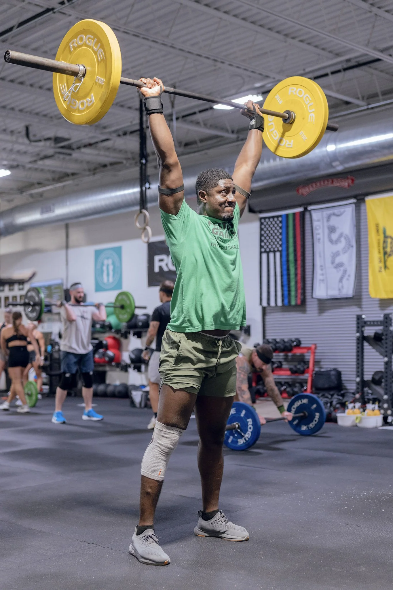 Member catching a jerk overhead with a loaded barbell