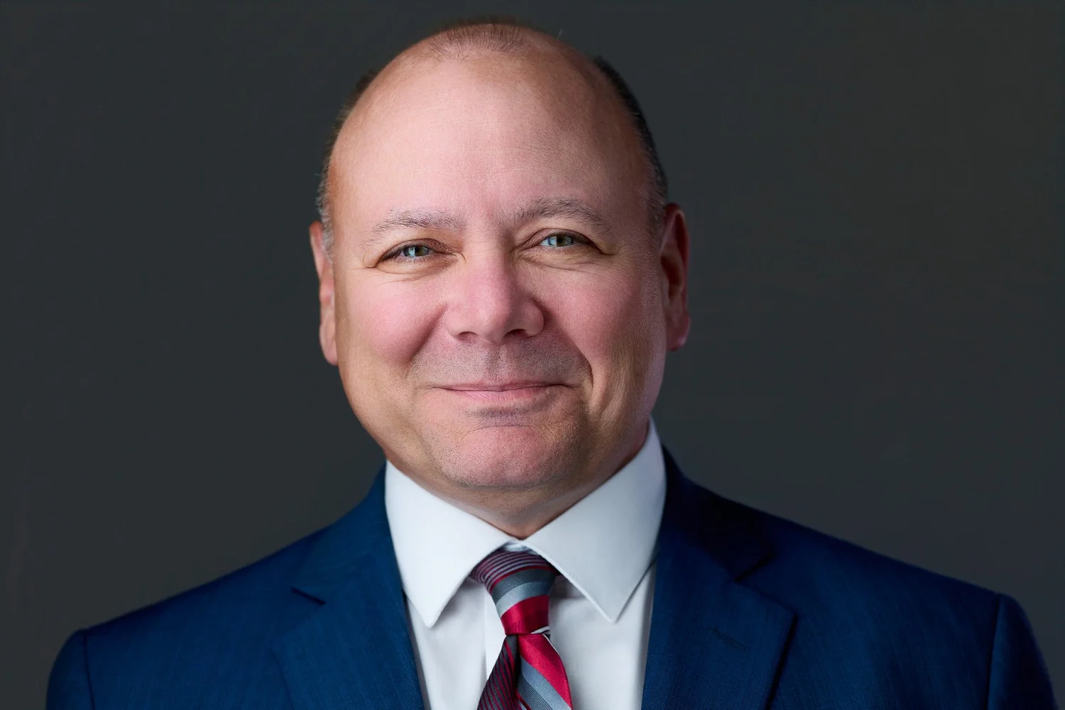 Executive headshot of a man in a blue suit and red tie, corporate headshots Syracuse NY