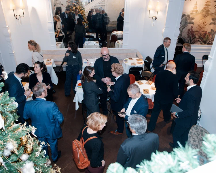 A photo of a group of people sitting around a table in discussion. Behind them we see a slide that says UK Clean Energy Investment Roundtable.